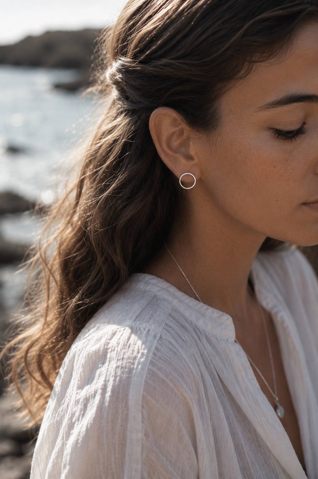 Woman wearing sterling silver circle earrings with a blurred natural background