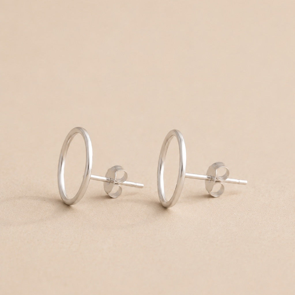 Pair of sterling silver circle stud earrings on a beige background