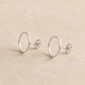 Pair of sterling silver circle stud earrings on a beige background