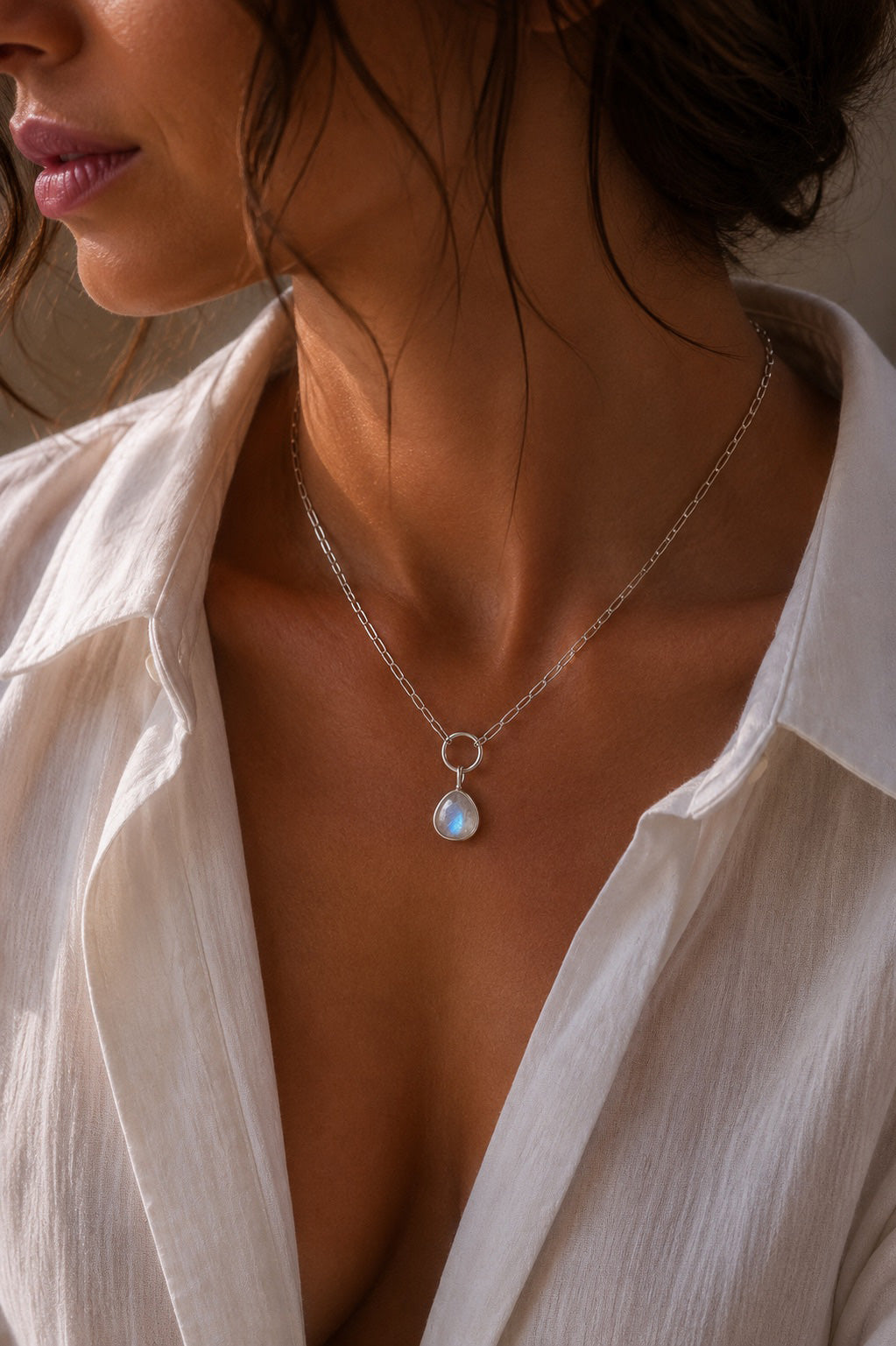 Model wearing a paperclip chain with a pebble shaped Unyezi Moonstone pendant by Rya Atelier. Faceted Rainbow Moonstone set in solid 925 sterling silver. 