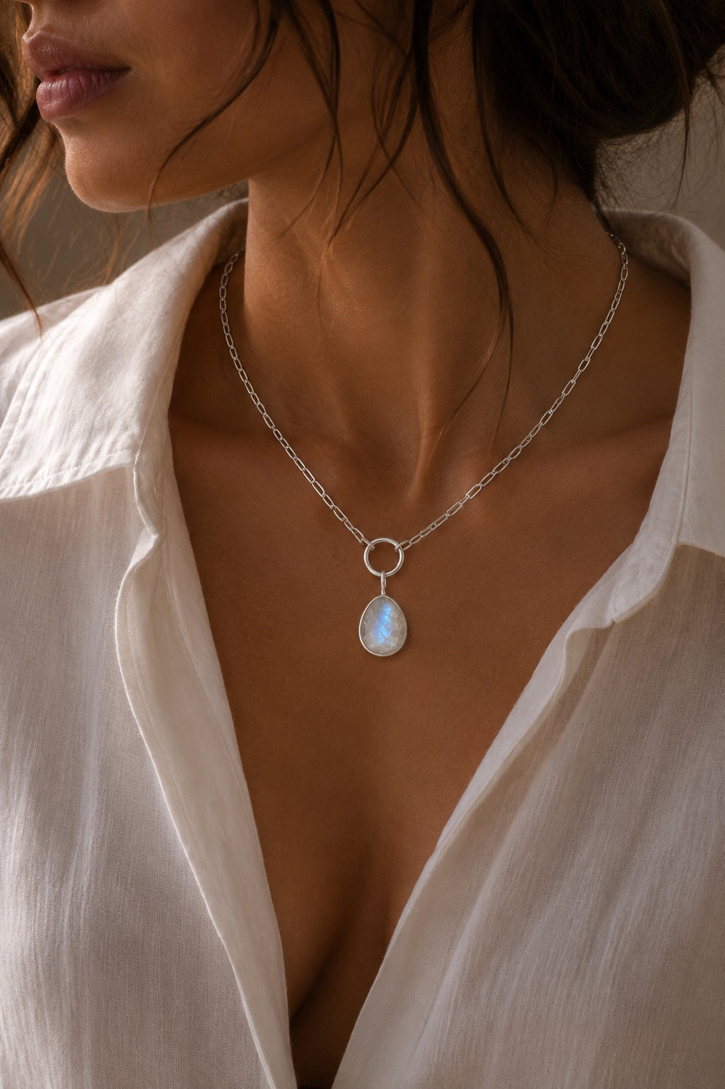 Model wearing a chain with the portrait oval shaped Unyezi Moonstone pendant by Rya Atelier. Faceted Rainbow Moonstone set in solid 925 sterling silver. 